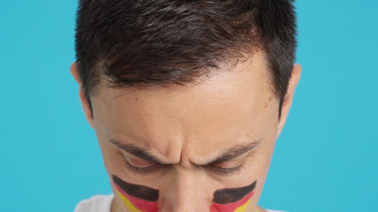 Serious man with a german flag painted on the face