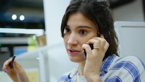 young woman having business talk on phone at office cubicle