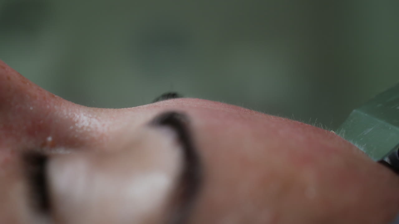 Female forehead with ultrasonic scrubber moving by it. Extreme close up. Skincare and beauty concept.