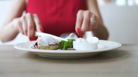 unrecognizable girl in red dress taking desert strudel at the restaurant using fork and knife. slow motion shot