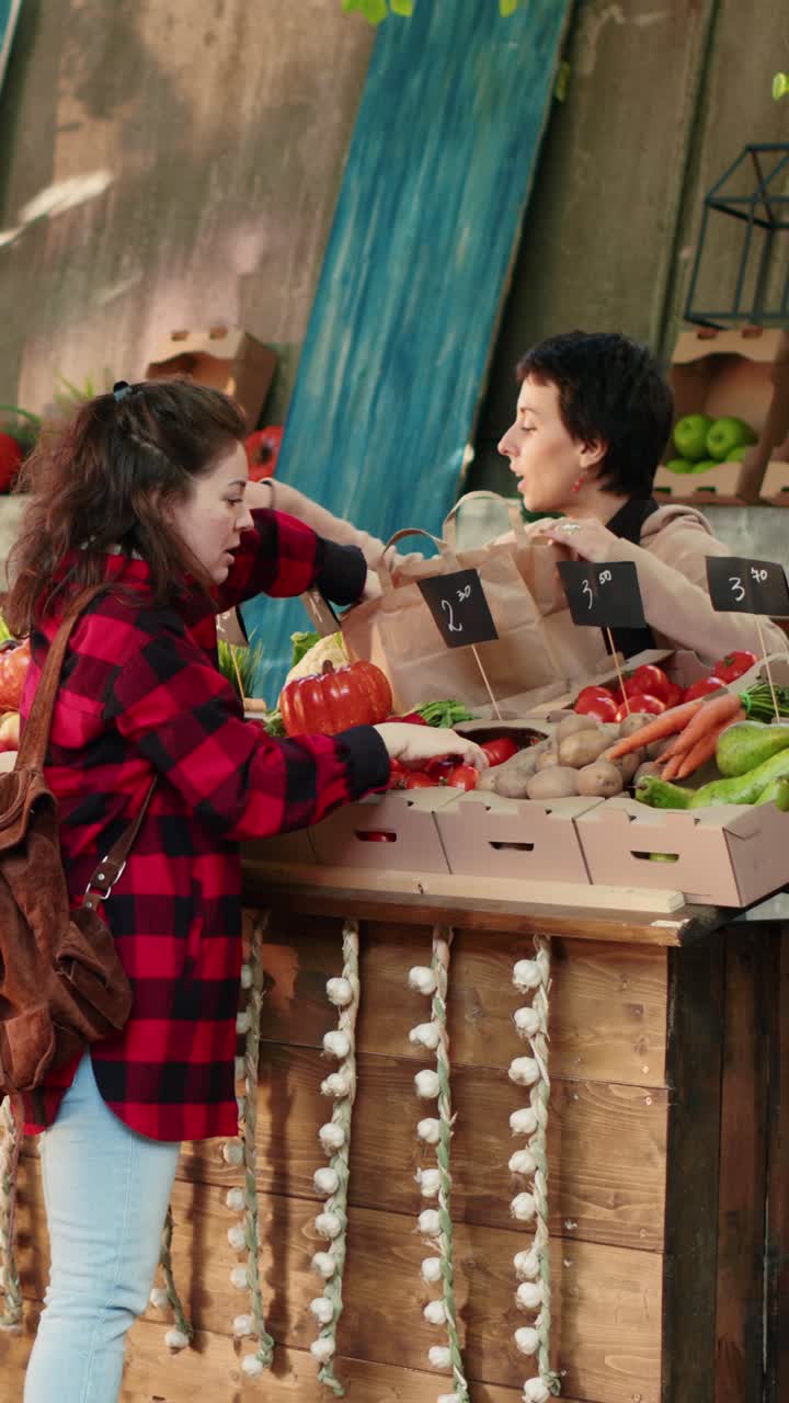 Vídeo vertical: suporte de feira feminino entregando frutas e verduras da estação para clientes