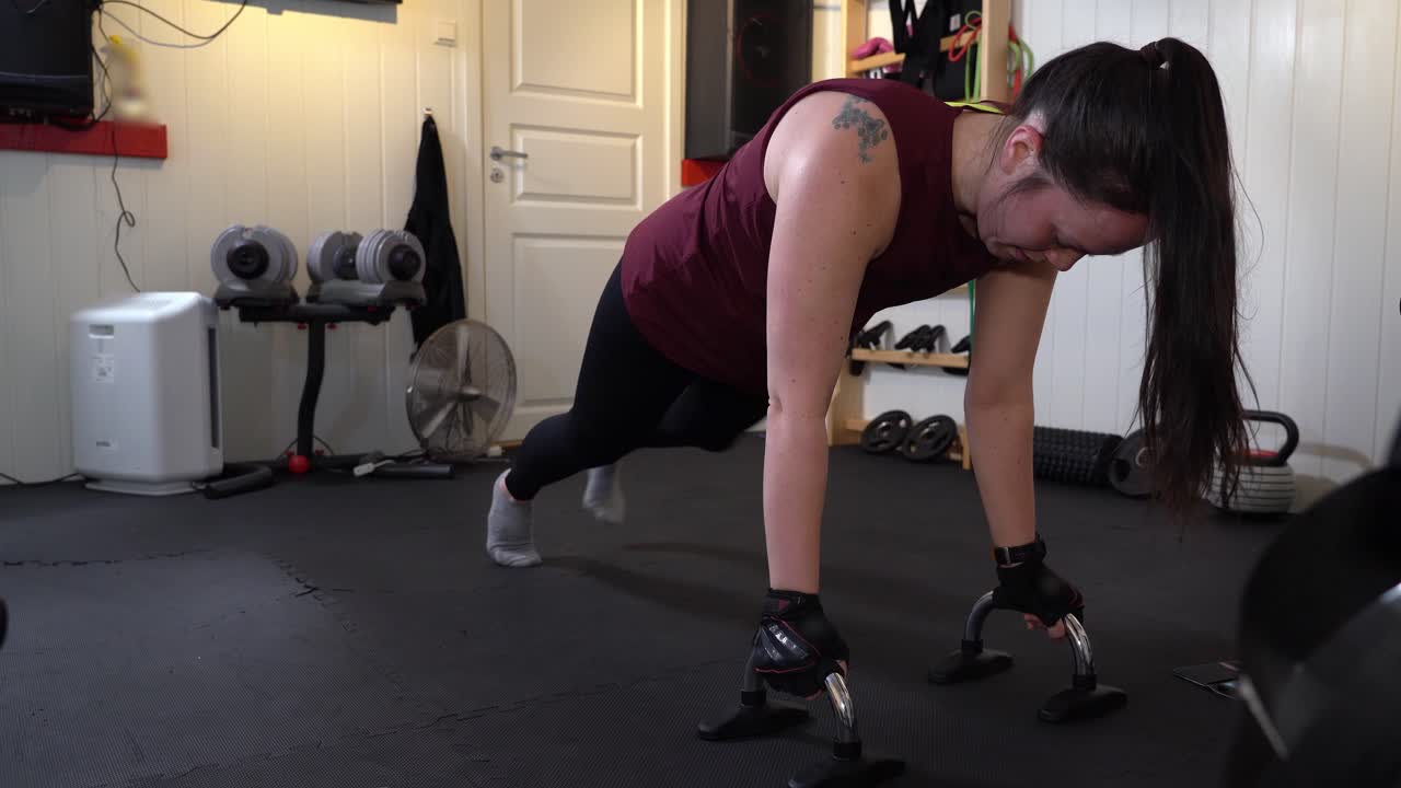 hembra realizando soporte de flexión con una sola pierna - entrenamiento solo en el sótano