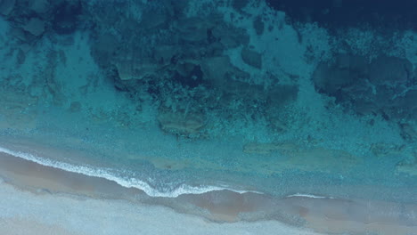 Aerial-descending-shot-of-a-sandy-beach-in-the-afternoon