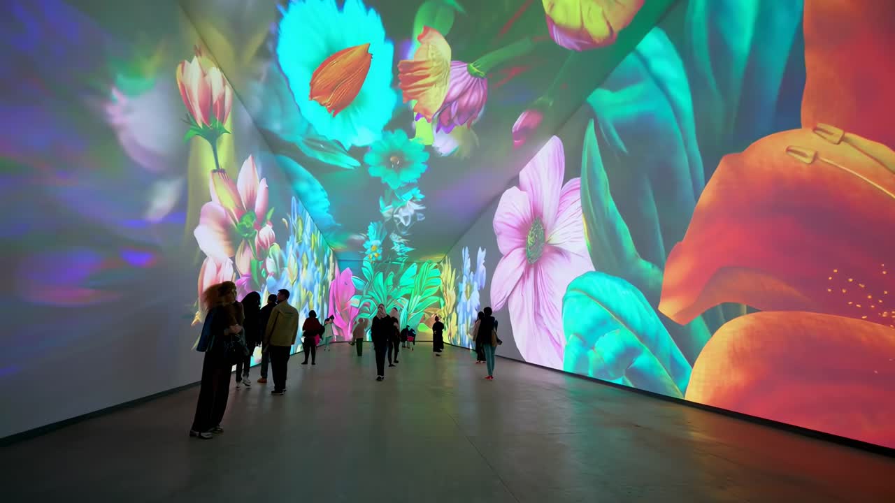 Inquadratura grandangolare di vivaci proiezioni video floreali sulle pareti, creando un'esperienza artistica immersiva.