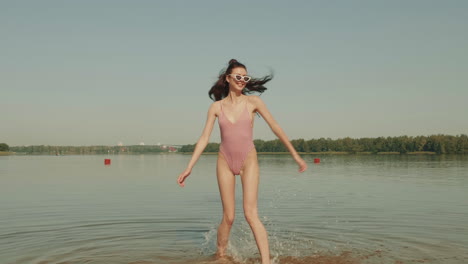 woman in a pink striped swimsuit by the river