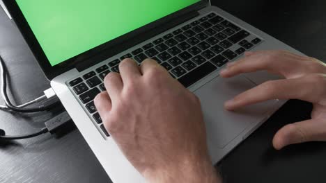 person is using chroma key green screen laptop computer. technology concept. businessman is working on pc at workplace, typing on keyboard. man is using laptop computer with laptop green screen