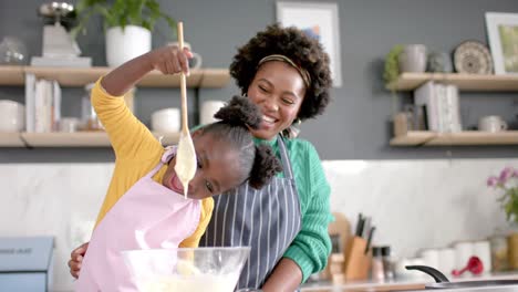 Happy-african-american-mother-and-daughter-preparing-dough-in-bowl-in-kitchen,-slow-motion