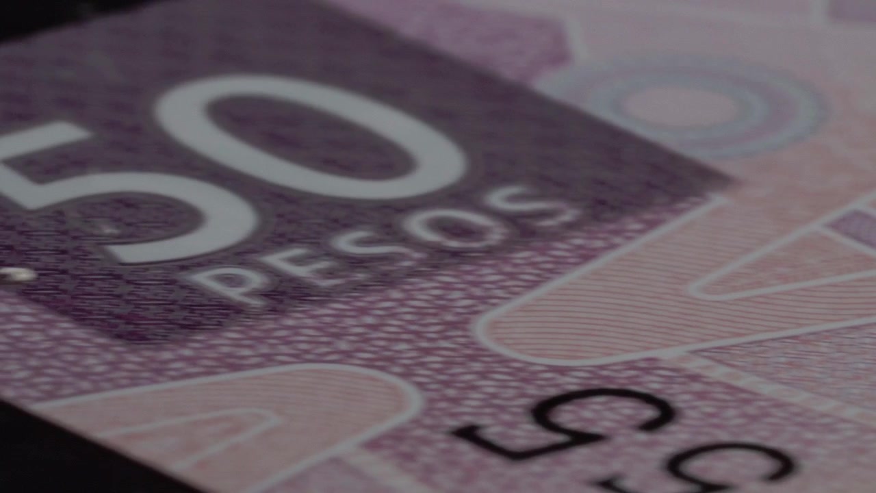 Yavaş kamera hareketi sırasında basılı kupürü, gravürlü detayları ve güvenlik özelliklerini vurgulayan Meksika 50 peso banknotunun makro yakın çekimi