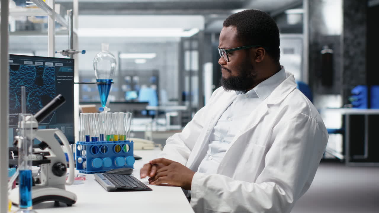Vertical video Lab technician at desk typing on PC keyboard, doing research tasks
