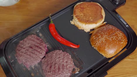 Practical-electric-griddle-searing-burgers-and-buns-on-countertop