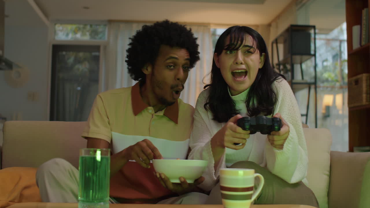 Mulher tentando vencer ao jogar videogame, sentada ao lado do namorado