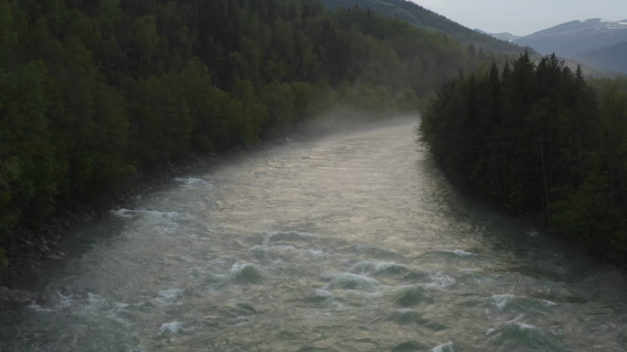 Flight over a foggy river. The mist is hanging low over the landscape creating a dark mystical mood over the whole scene