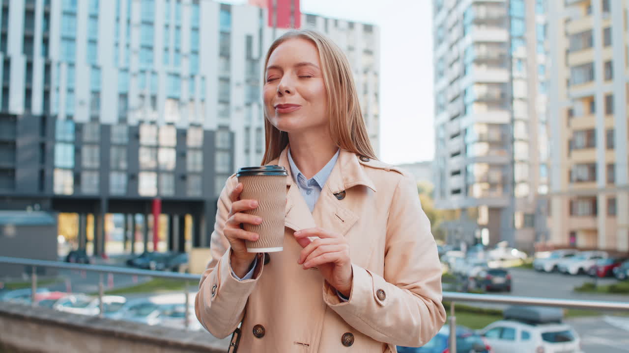 Happy mature businesswoman enjoying morning coffee hot drink and smiling on downtown city street