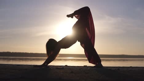 una mujer caucásica practicando yoga al aire libre. silueta aislada en una puesta de sol y mar en el fondo