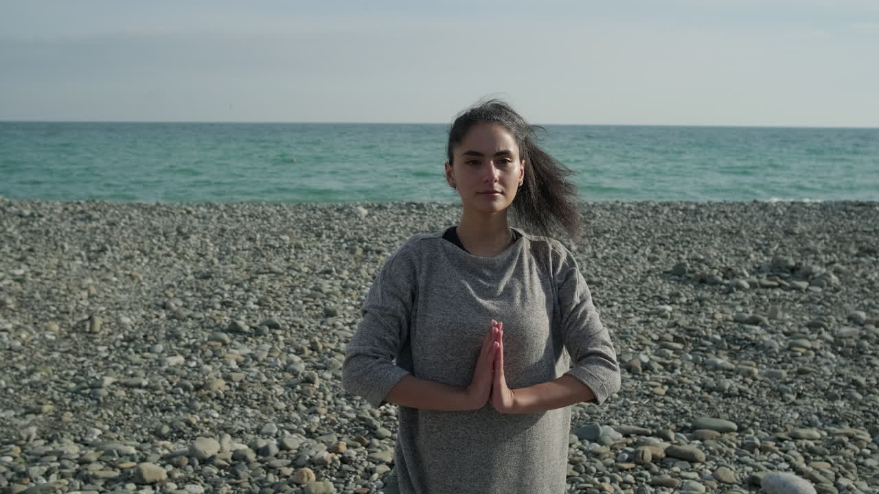 Una mujer joven meditando en la playa.