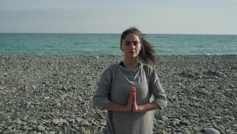 una joven meditando en la playa.