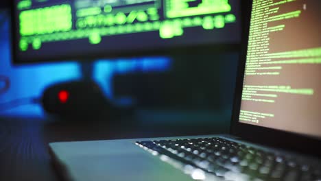 computer equipment with programming code on screens on table in dark room