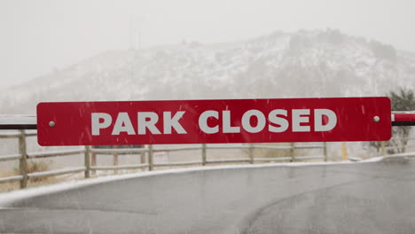 close up of park closed sign in winter snow storm
