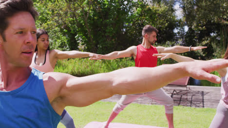 grupo diverso practicando yoga con instructor masculino de pie en un parque soleado