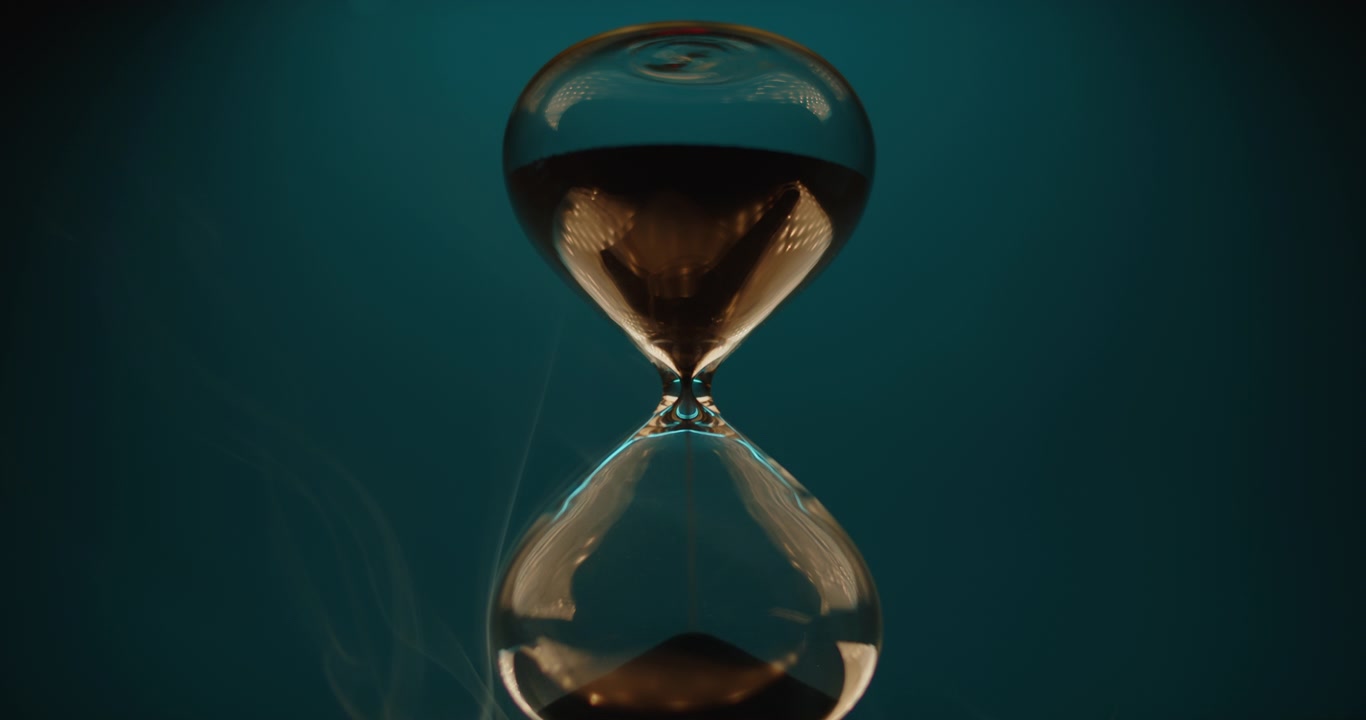 Hourglass and smoke on teal background