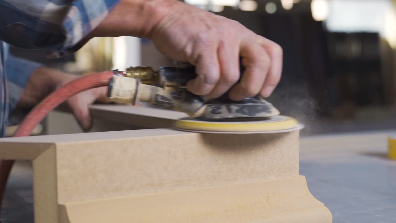 男性の木工が木を砂にする.