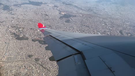 a beautiful high angle view of the city of kathmandu, nepal while looking out over the wing of a nepal airlines jet