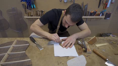 craftsman flattening wooden piece with scraper in workroom