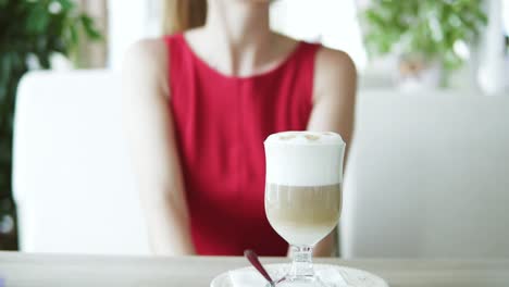 pretty young woman with long blond hair in red combination sitting in cafe with late and waiting for someone. slow motion shot