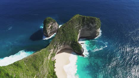 sweeping aerial view of kelingking beach’s cliffside and turquoise waters off nusa penida, bali, establishing