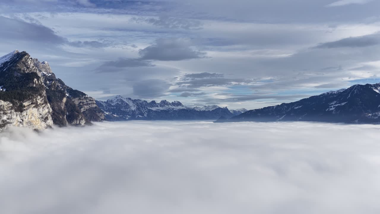Aerial view of Churfirsten mountain range above the fog-covered Walensee near Amden, Switzerland on a calm winter day