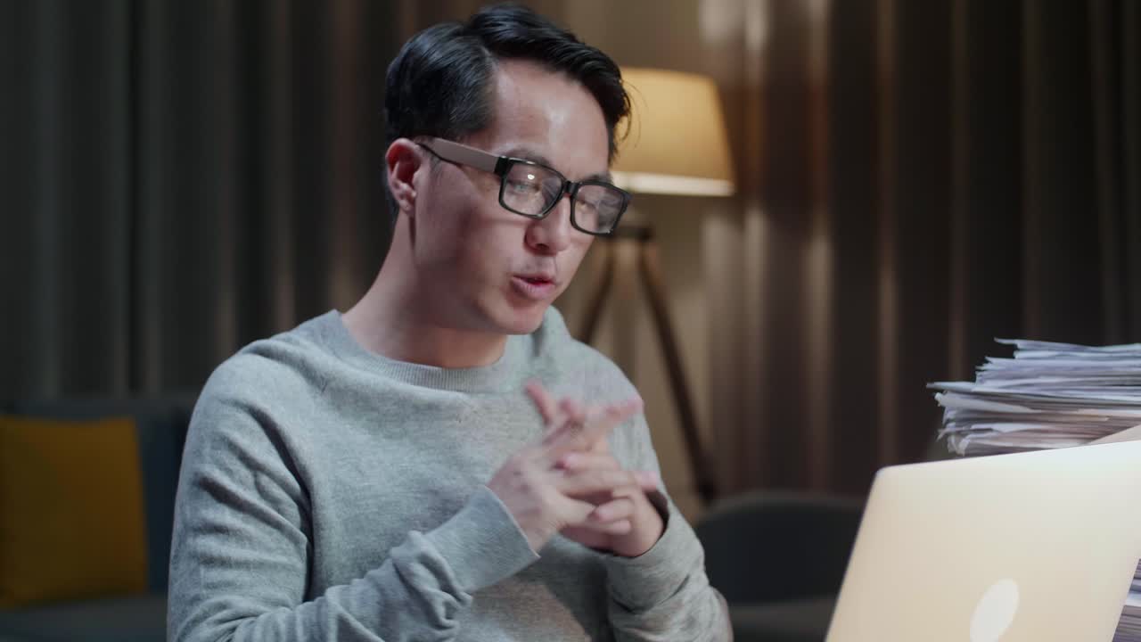 집에서 노트북으로 비디오 통화를 하는 동안 일을 설명하는 아시아 남자의 클로즈업