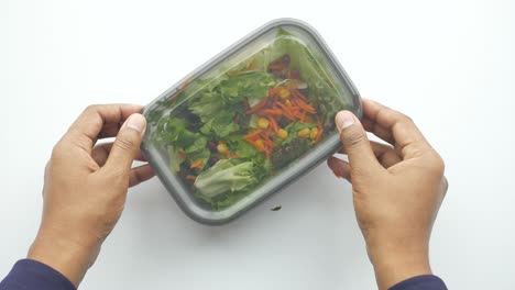 manos sosteniendo un recipiente de ensalada