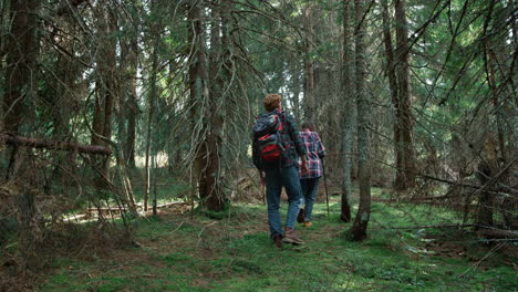 Smiling-hikers-walking-in-forest.-Couple-of-tourists-trekking-between-trees