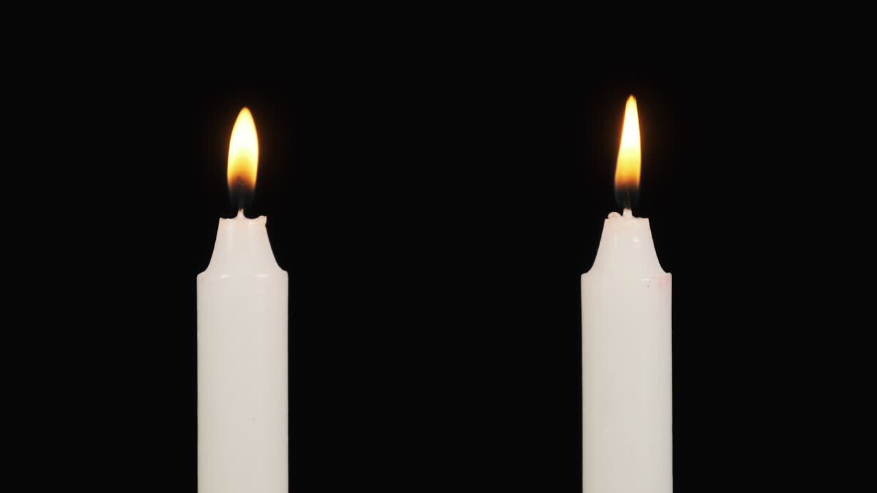 Due candele bruciano su uno sfondo nero nelle vicinanze. Spegni le candele