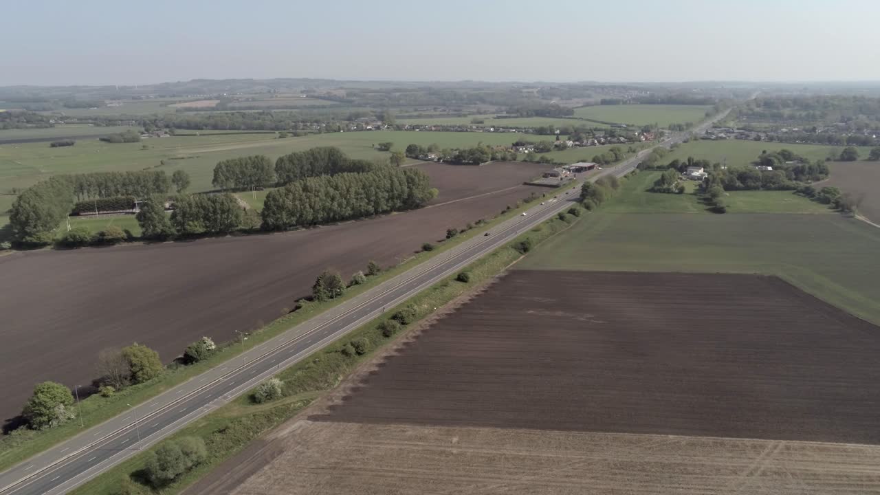 Drone aerial view dolly left above British A580 East Lancs highway in rural agricultural countryside
