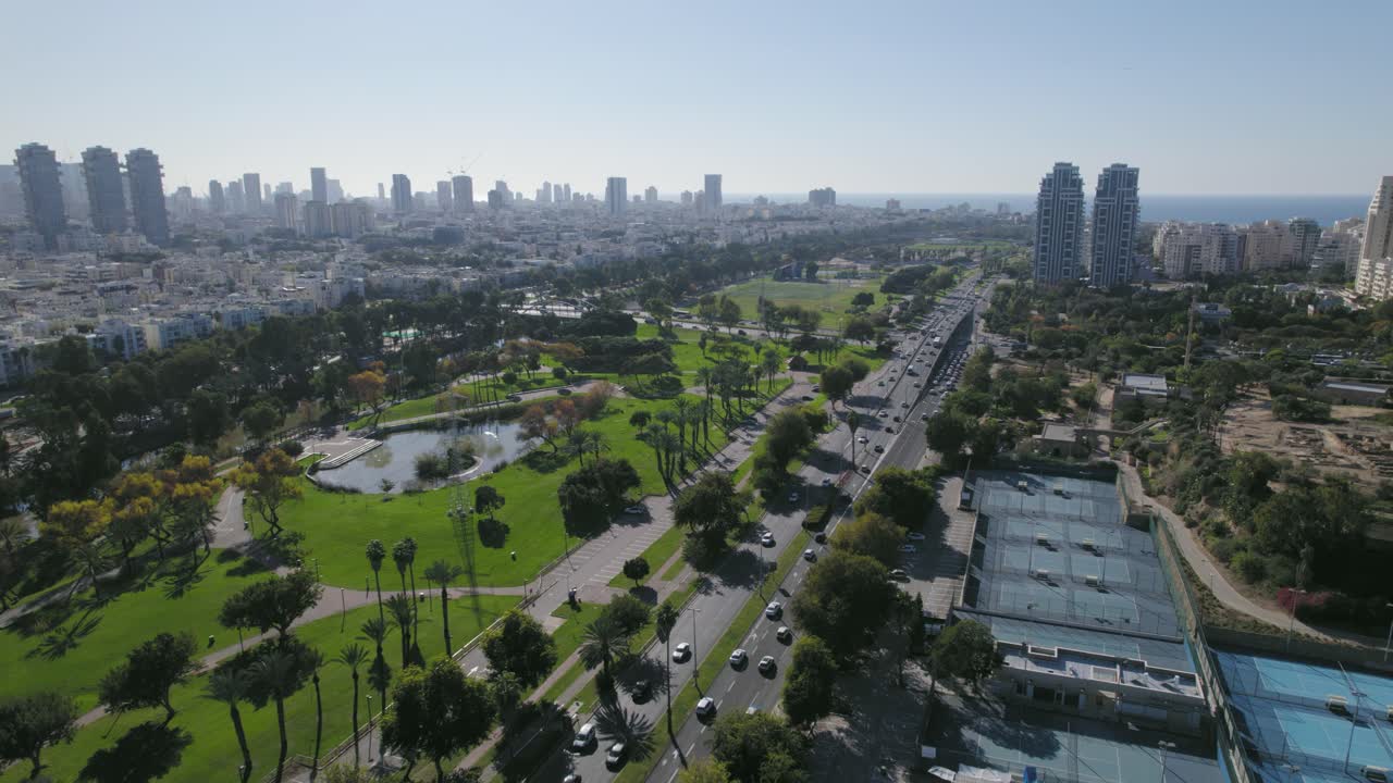 tiro de paralaxe sobre quadras de tênis com uma pitoresca paisagem urbana de um parque e rio perto de torres residenciais
