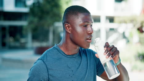 man drinking water after exercising outdoors