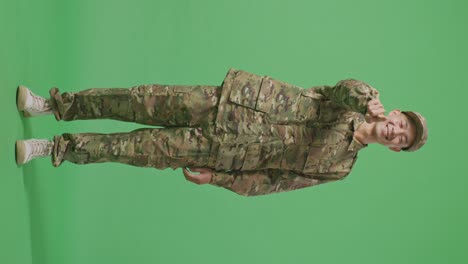 full body of asian man soldier smiling and touching his chest then pointing at you while standing in the green screen background studio