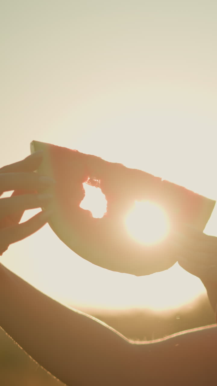 밝은 빛에 대한 별 모양의 절단으로 수박 조각을 들고 있는 여성, 만적이고 창의적인 실루 효과를 만들어, 조명 된 과일 조각과 빛을 함께