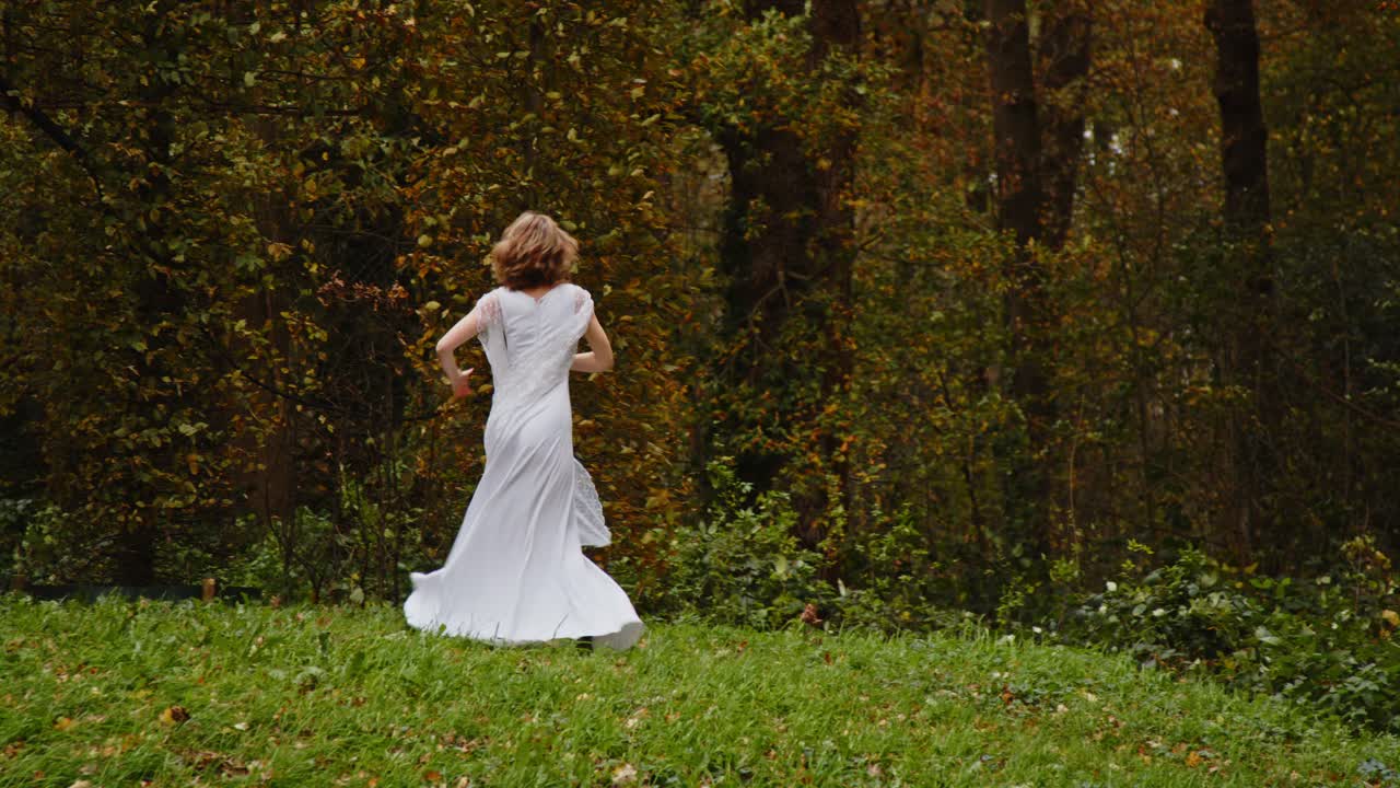 Ampia veduta di una donna con un abito lungo e ampio che fa piroette in una foresta