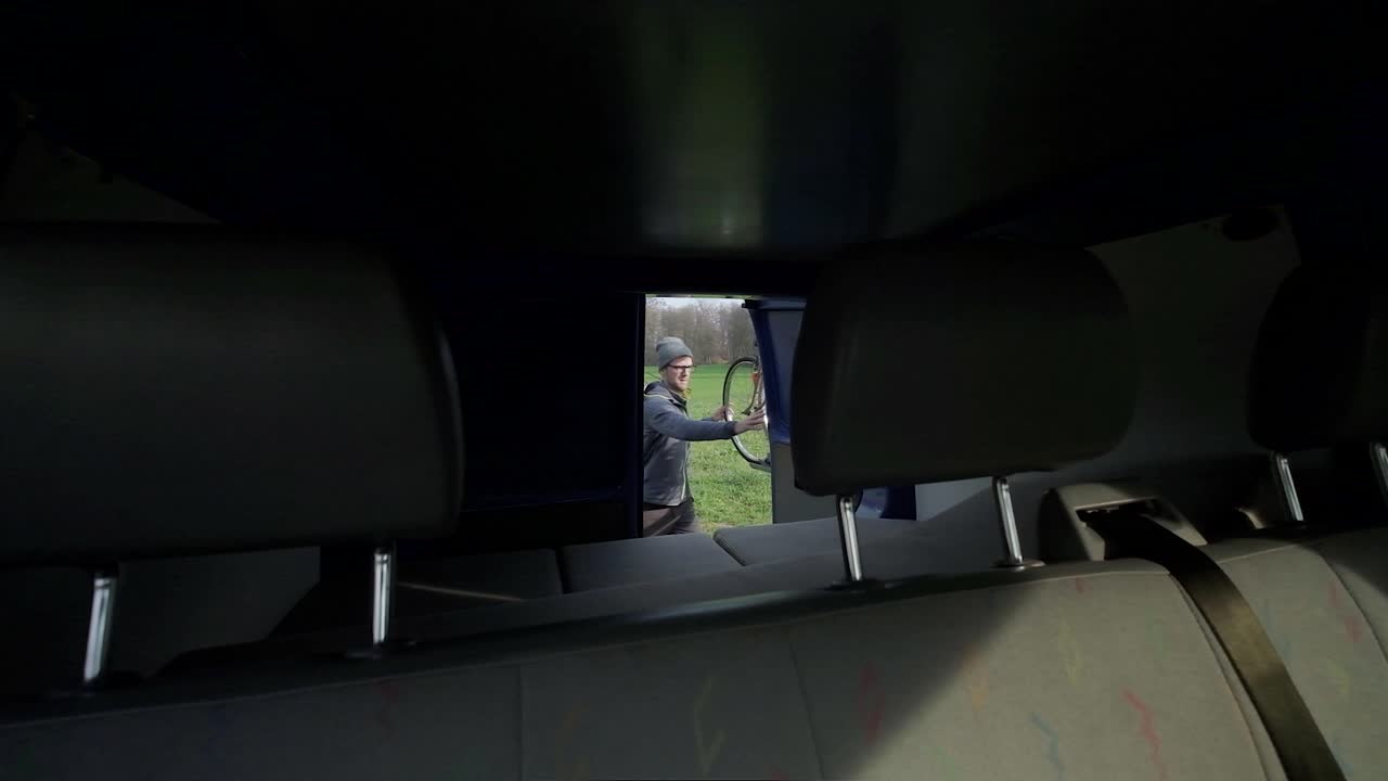 Kamera auf dem Rücksitz eines Lieferwagens, als ein Mann die Hintertür des Wohnmobils öffnet. Ein Paar reist in einem Wohnmobil.
