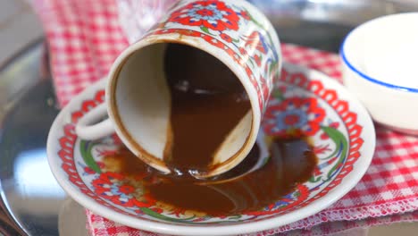 turkish coffee pouring from cup onto saucer