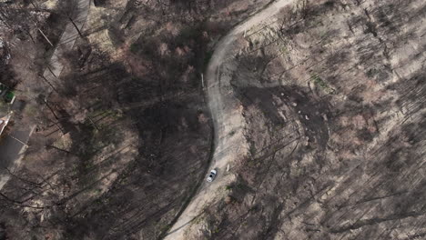 Vista-Superior-De-La-Conducción-De-Automóviles-En-El-Camino-Rural-Entre-El-Bosque-Quemado-En-El-Pont-De-Vilomara,-España---Toma-Aérea-De-Drones