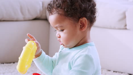 black toddler sitting and playing with plastic rings