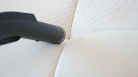 cleaning a white couch with a vacuum cleaner