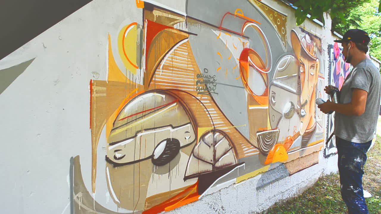 Kunstneren tegner graffiti på et gjerde. Graffiti på et gjerde