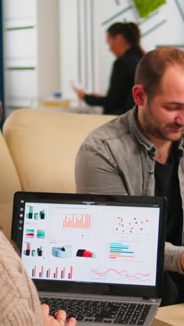 vertical video close up of back view young entrepreneur sitting on couch in office using laptop