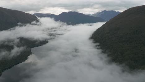 breathtaking aerial wide angle shot of low hanging clouds sitting below the mountain range near the manso river, argentina