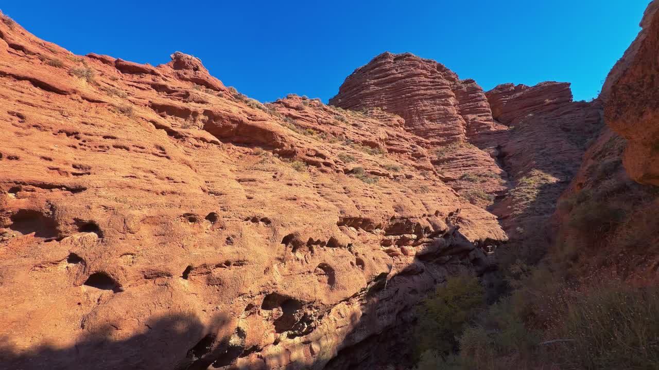 Pingshan Lake Grand Canyon, Zhangye, provincia di Gansu, Cina - Imponenti pareti di roccia rossa si ergono ripide sotto un cielo blu intenso - Ripresa con panoramica verso destra