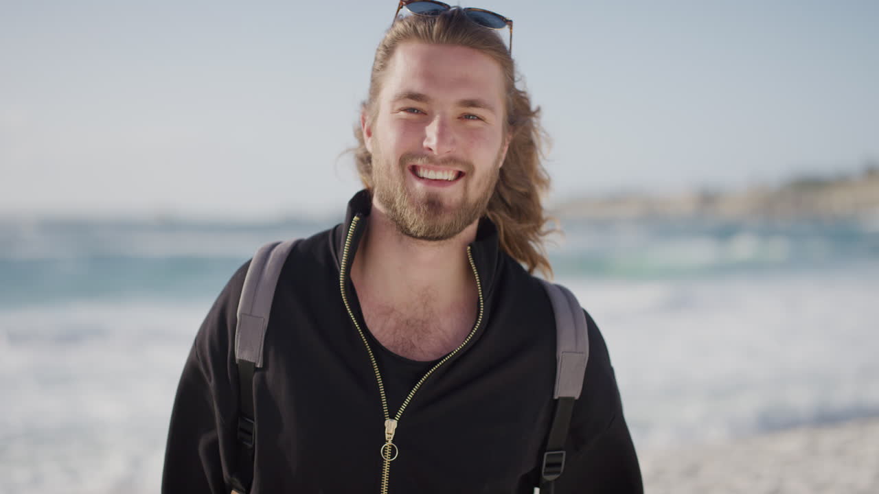 해변에서 따뜻한 여름 휴가 날을 즐기고 해변에서 카메라를 보고 행복하게 미소 짓는 예쁜 젊은 남자의 초상화